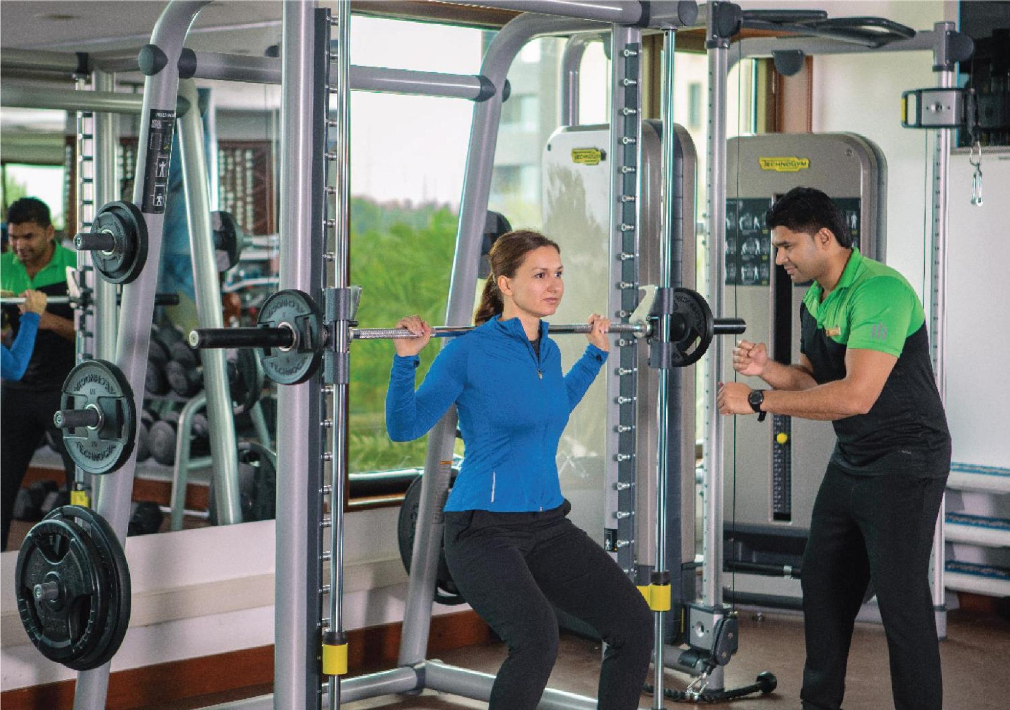 Jumeirah Messilah Beach Kuwait Kuwait City Eksteriør billede A personal trainer assisting a woman with a weight training exercise